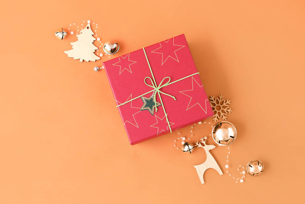 Рождественская подарочная коробка с мячами и фигурками ели и оленя на цветном фоне - Фото, изображение