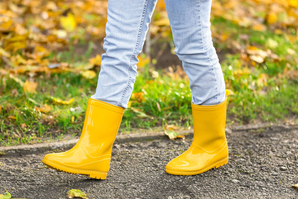 Woman in yellow gumboots walking in autumn park - Photo, Image