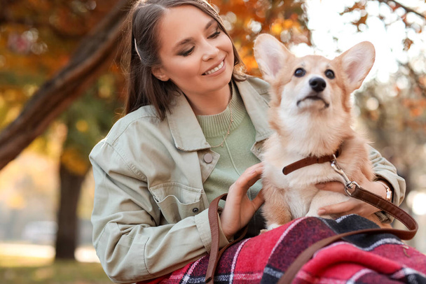 Νεαρή γυναίκα με χαριτωμένο Corgi σκυλί στο πάρκο φθινόπωρο - Φωτογραφία, εικόνα