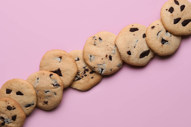 Tasty cookies with chocolate chips on pink background - Valokuva, kuva