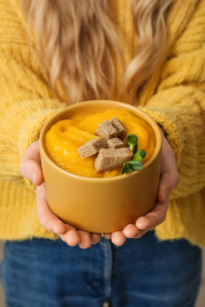 Kobieta trzyma miskę smacznej zupy z kremu dyniowego, zbliżenie - Zdjęcie, obraz