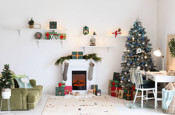 Εσωτερικό εορταστικού σαλονιού με σύγχρονο χώρο εργασίας, χριστουγεννιάτικα δέντρα και τζάκι - Φωτογραφία, εικόνα