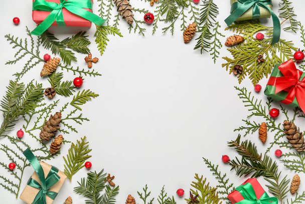 Frame made of coniferous branches, gift boxes, cones and berries on white background, closeup - Photo, Image