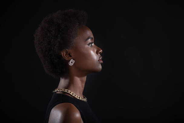 Ritratto ravvicinato di donna afro-americana con acconciatura afro su sfondo nero - Foto, immagini