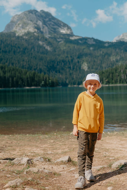 Niño se encuentra en la orilla de un lago de montaña, Lago Negro, Parque Nacional Durmitor, Montenegro - Foto, imagen