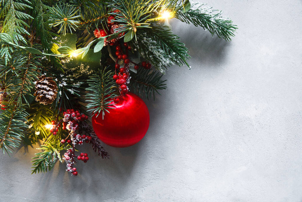 Kerst behang, gemaakt van sparren takken, rode ballon, rode bessen, lichten en tegens op grijze achtergrond. Kerst behang. - Foto, afbeelding