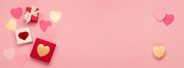Roze papieren hartjes en feestelijke geschenkdoosjes op roze achtergrond. Valentijnsdag banner concept. Platte lay, bovenaanzicht, kopieerruimte. Vakantie wenskaart voor Valentijnsdag, Vrouw of Moederdag, Verjaardag. - Foto, afbeelding