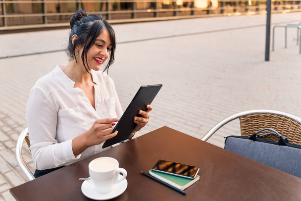 businesswoman using digital tablet on the terrace of a coffee shop, concept of digital entrepreneur and urban lifestyle, copy space for text - Φωτογραφία, εικόνα