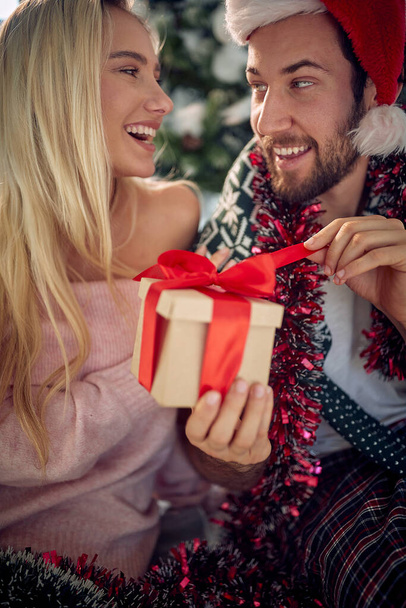 Happy woman surprising her men girl with a present at Christmas.. - Foto, afbeelding