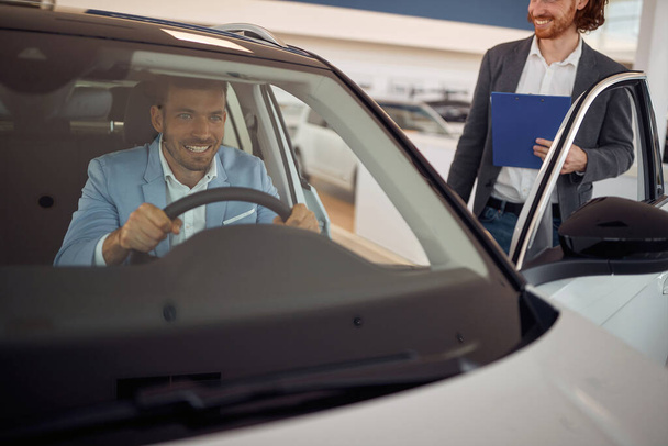 Successful caucasian male buying a car for himself in the store - Photo, image