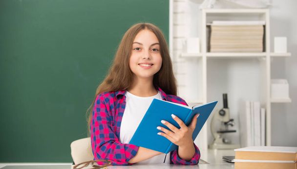 felice bambino studio con libro a scuola su sfondo lavagna, saggezza - Foto, immagini