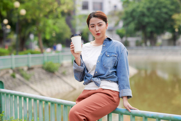  beautiful female with coffee to go cup looking at camera during leisure - Фото, изображение