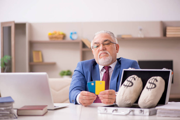 Old male employee in remuneration concept at home - 写真・画像