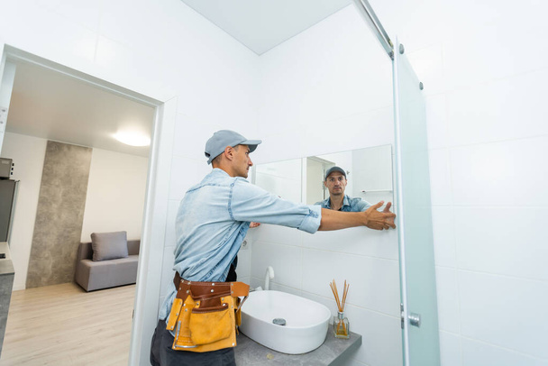 Handyman installeren spiegel in de badkamer. - Foto, afbeelding