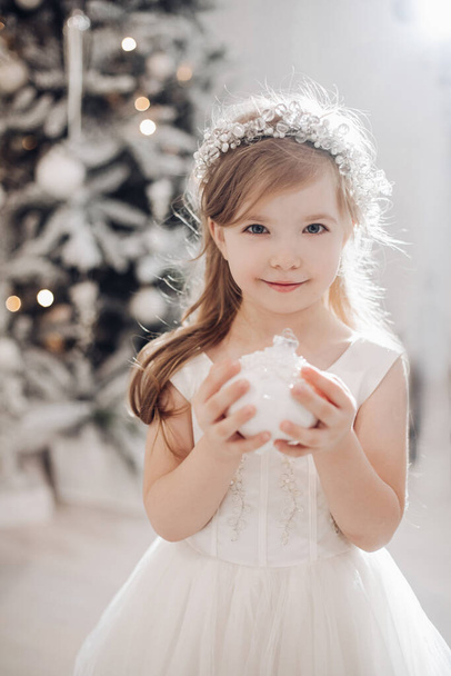 portrait of beautiful little child holds a white christmas toy and smiles - Foto, Imagem