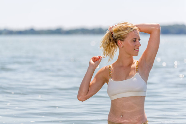 Mladý atraktivní blondýny dívka s perfektní sportovní tělo v bikinách na pláži v létě - Fotografie, Obrázek