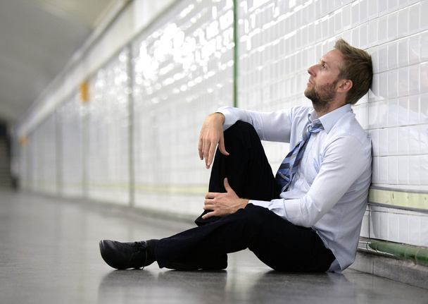 Young businessman lost in depression sitting on ground street subway - Фото, зображення