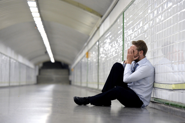 Young businessman lost in depression sitting on ground street subway - Photo, Image