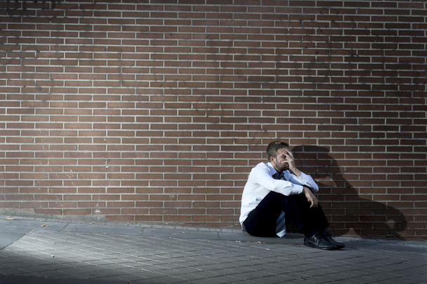 Бизнесмен, потерявший работу, впал в депрессию, сидя на углу городской улицы
 - Фото, изображение