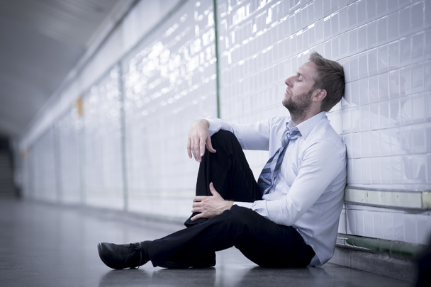 Young businessman lost in depression sitting on ground street subway - Foto, Bild