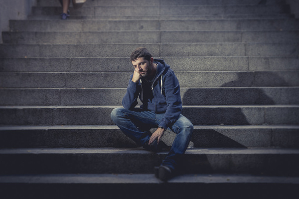 Молодий чоловік загубився в депресії, сидячи на першій вулиці бетонних сходах
 - Фото, зображення