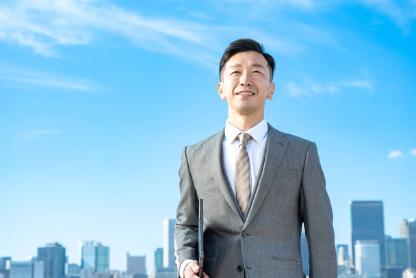Портрет бизнесмена, голубое небо и здания большого города - Фото, изображение