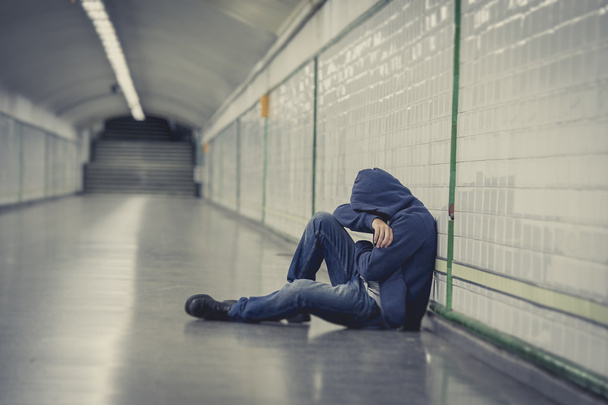 jonge man verloren in depressie zittend op grond straat metro tunnel - Foto, afbeelding