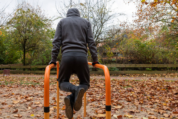 Workout, sportsman pull ups the horizontal bar, outside, autumn. - Photo, Image