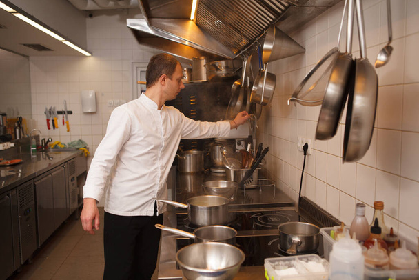 Chef working at the restaurant kitchen, using kitchenware - Foto, Imagen