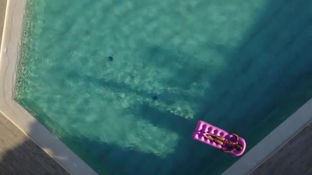 κοριτσάκι που επιπλέει σε ένα φουσκωτό στρώμα στην πισίνα - Πλάνα, βίντεο