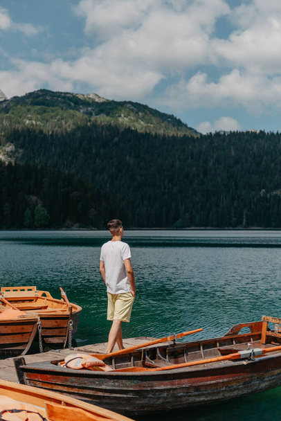 Young man looking at Black Lake, Durmitor National Park, Zabljak, Montenegro. Hipster traveler enjoying view of Black Lake - 写真・画像