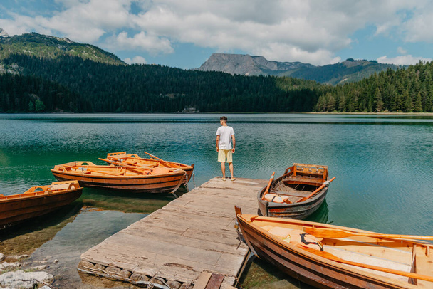 Young man looking at Black Lake, Durmitor National Park, Zabljak, Montenegro. Hipster traveler enjoying view of Black Lake - Foto, afbeelding