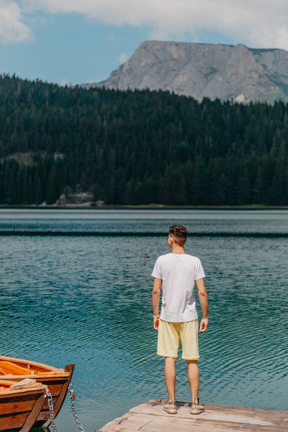 Young man looking at Black Lake, Durmitor National Park, Zabljak, Montenegro. Hipster traveler enjoying view of Black Lake - Φωτογραφία, εικόνα