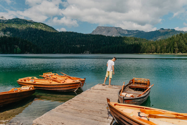 Young man looking at Black Lake, Durmitor National Park, Zabljak, Montenegro. Hipster traveler enjoying view of Black Lake - Photo, Image