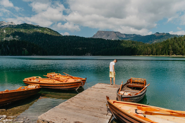 Young man looking at Black Lake, Durmitor National Park, Zabljak, Montenegro. Hipster traveler enjoying view of Black Lake - Фото, зображення
