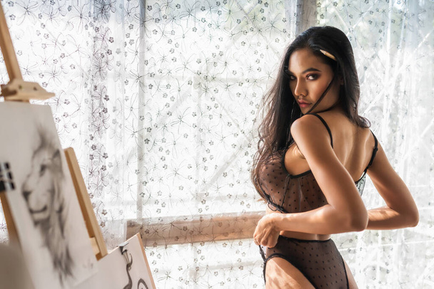 Retrato de hermosa joven asiática sexy mujer con negro ver a través o cordón Bralette Transparente Sujetador hueco con pincel en la galería de arte. - Foto, Imagen