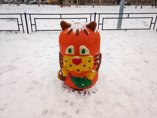 Una statua di un gatto rosso in un parco giochi in una giornata invernale. - Foto, immagini