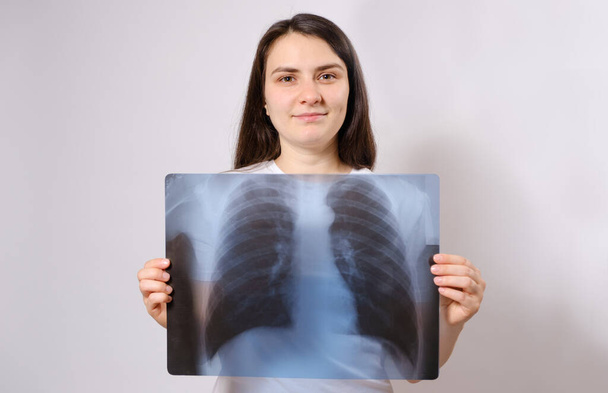 The woman holds an X-ray image of her lungs at chest level - Photo, Image