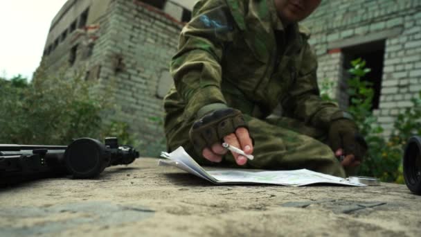 Ένας στρατιωτικός εξετάζει ένα χάρτη της περιοχής και καπνίζει ένα τσιγάρο. - Πλάνα, βίντεο