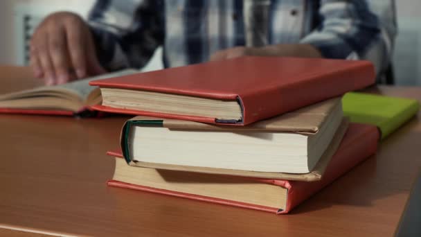 egy halom könyv fekszik egy olvasó íróasztalán a könyvtárban. - Felvétel, videó