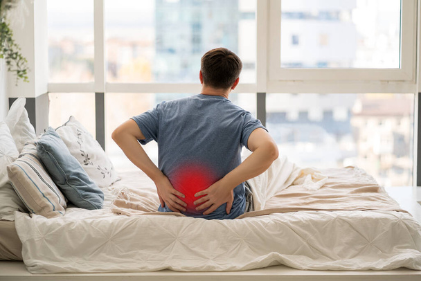 Back pain, kidney inflammation, man suffering from backache at home, painful area highlighted in red - Fotografie, Obrázek
