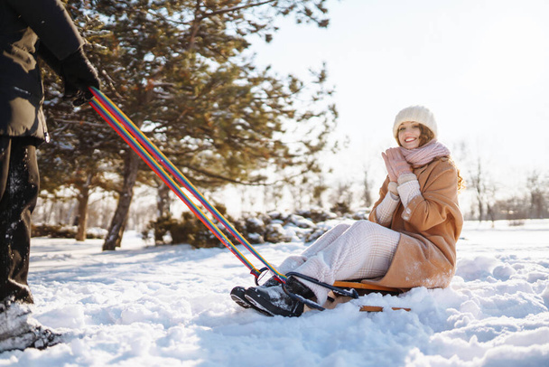 Ein junges Paar hat Spaß und rollt auf einem Schlitten durch den winterlich verschneiten Wald. Natur, Urlaub, Reisekonzept. - Foto, Bild