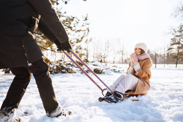 Young couple having fun and  rolls on a sled in the winter snowy forest. Nature, holidays, travel concept. - 写真・画像