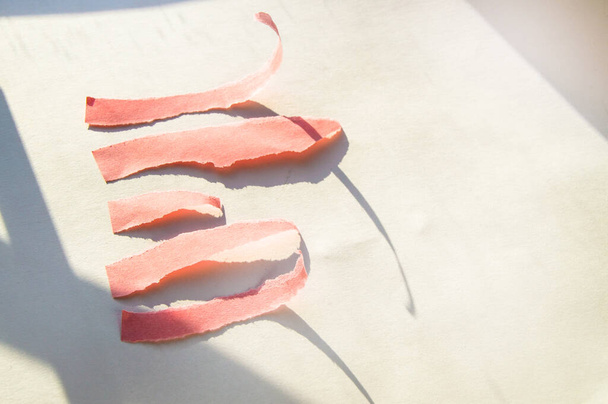 Streszczenie różowe podarte paski papieru na białym tle z cieniem światła słonecznego - Zdjęcie, obraz