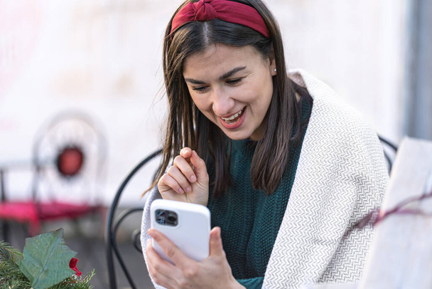 Attractive young woman uses smartphone, Christmas online shopping. - Photo, Image