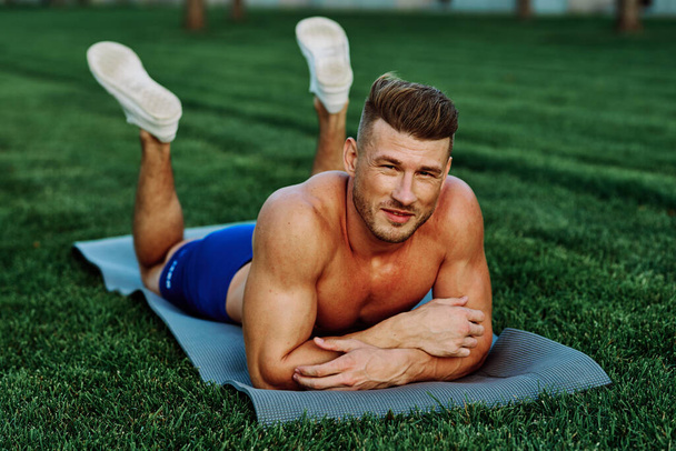 athletic man with pumped up muscular body in the park doing exercise - Foto, Imagem