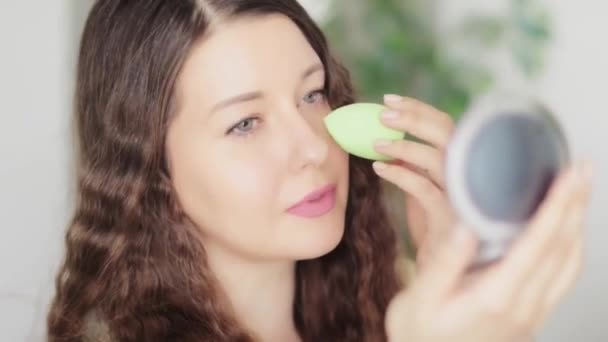 Beautiful woman applying natural organic makeup using beauty blender and smiling, eco make-up sponge tool, face portrait of caucasian model or vlogger as cosmetic product, skincare and people concept - Footage, Video