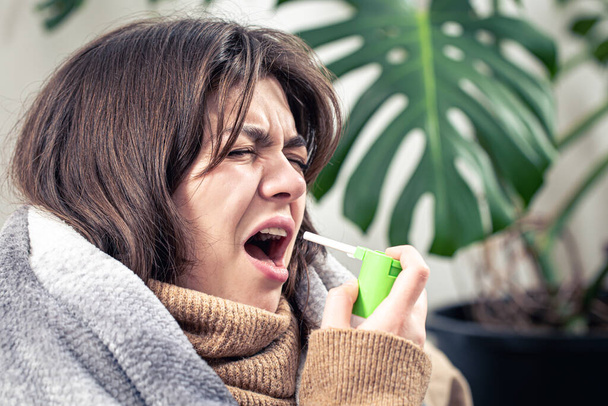 A sick young woman using cough spray. - Photo, Image