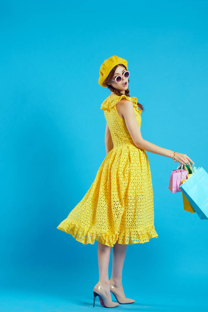 cheerful woman yellow dress shopping fun blue background - Foto, imagen