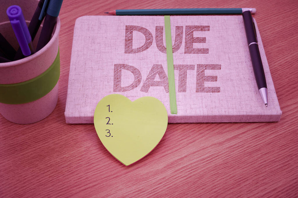 Sign displaying Due Date. Internet Concept The date when payment should be received by the person or company Plain Blank Open Notebooks With Stack Of Pens Container Over Table. - Photo, Image